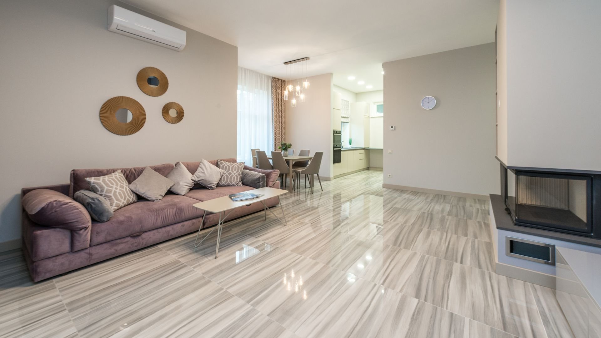 Modern living room with purple sofa, decorative mirrors, and open kitchen