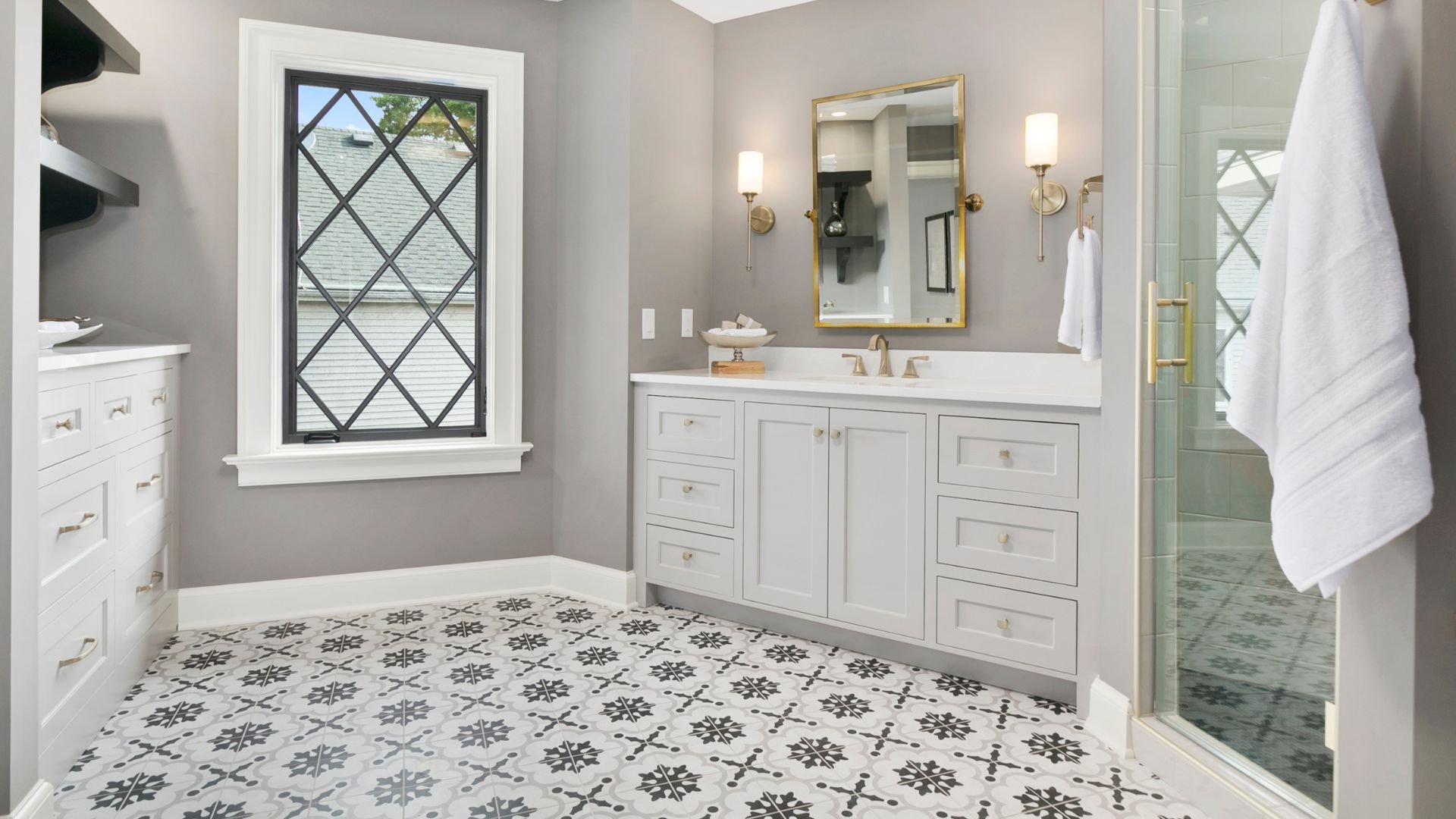 Elegant white bathroom with patterned floor and gold-framed mirror